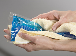 Hands wrapping ice pack in towel.