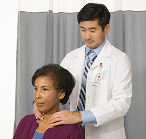 Health care provider feeling woman's neck to examine thyroid.