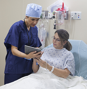 Health care provider talking to woman in pre-op hospital room.