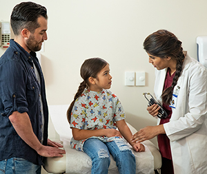 Healthcare provider listening to girl's chest with stethoscope.