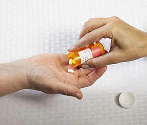 Healthcare provider giving woman medication in bed.