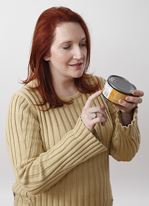 Woman reading nutrition label on can.