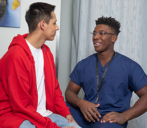 Health care provider talking to man in exam room.