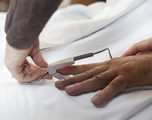 Pulse oximeter being clipped onto person's finger.