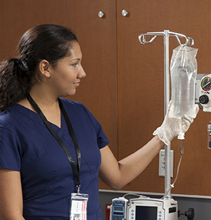 Proveedora de atención médica revisando la bolsa para infusión intravenosa.